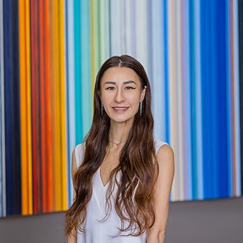 Woman smiling in white dress, colorful striped background.