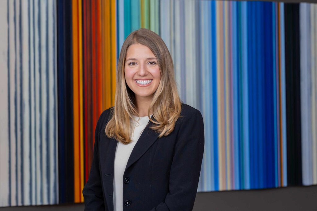 Professional woman smiling before colorful striped background.