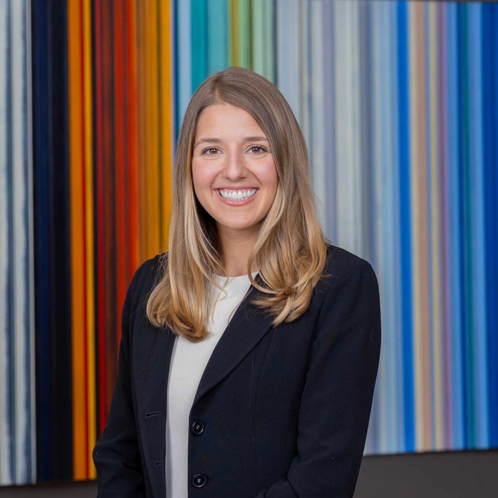 Team 32 Professional woman smiling before colorful striped background.