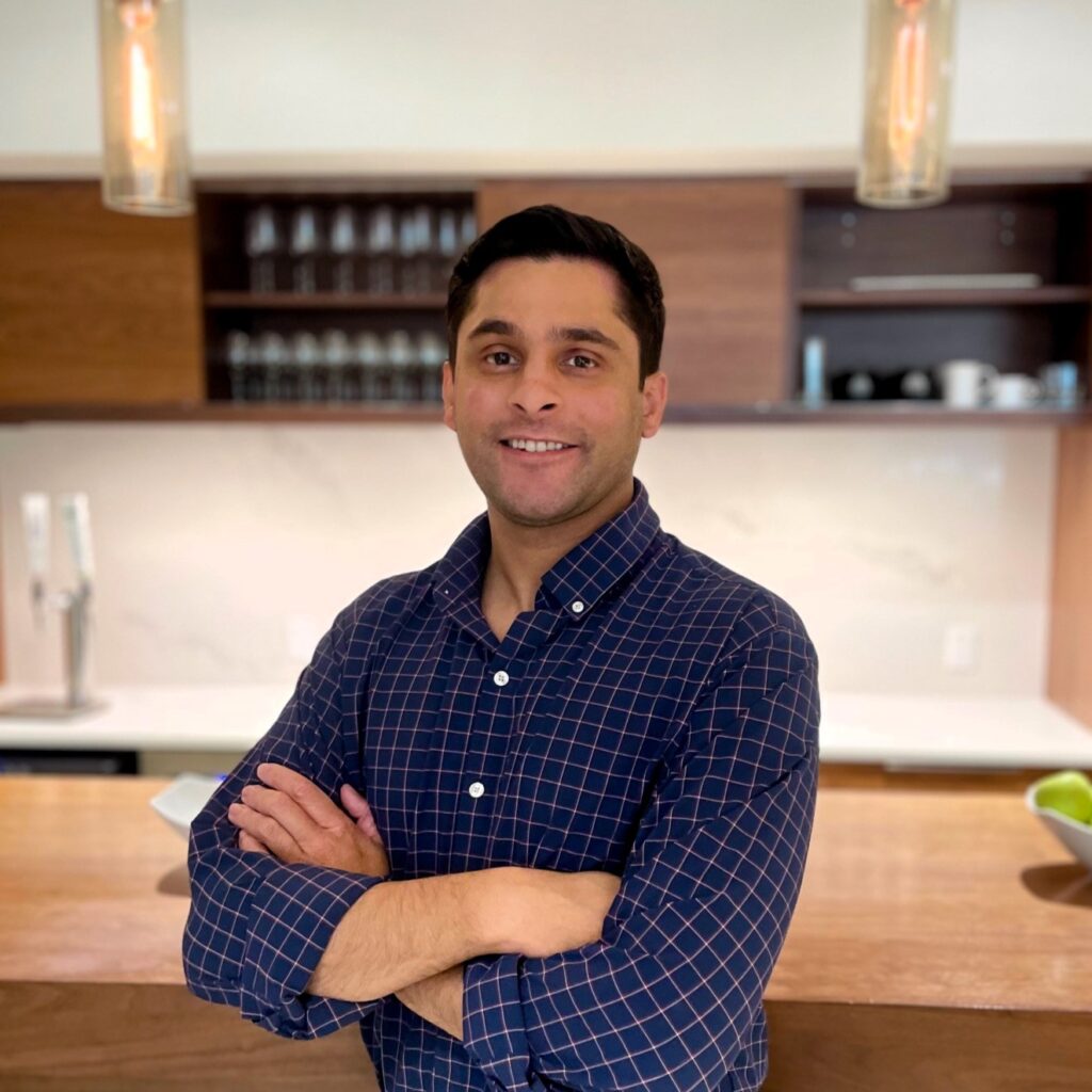 Man smiling with arms crossed in modern kitchen.