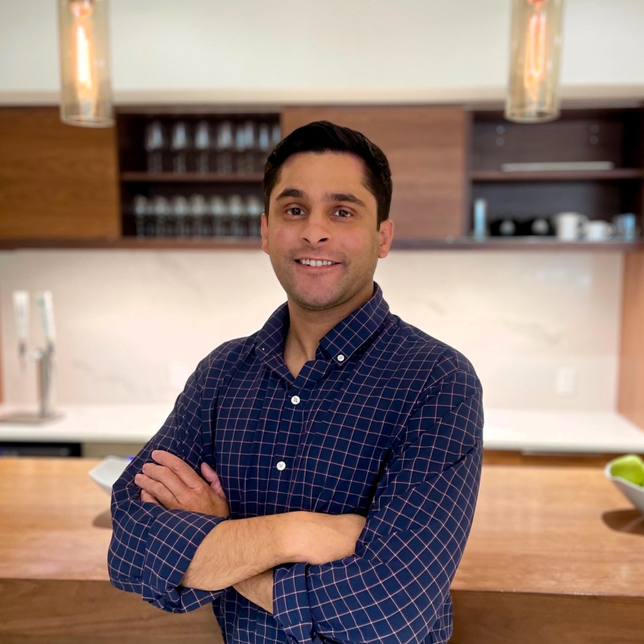 Jay 1 Man smiling with arms crossed in modern kitchen.